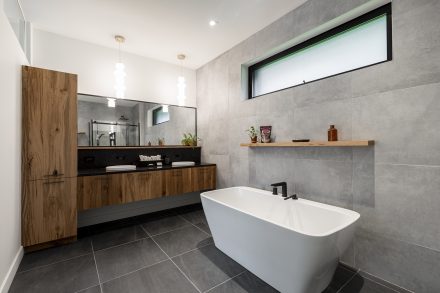 Interior of a modern bathroom with neutral tones and a separate bathtub.